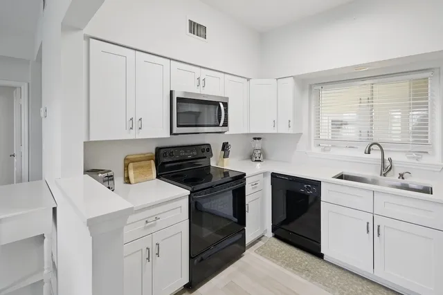 a kitchen with white cabinets sink and stainless steel appliances
