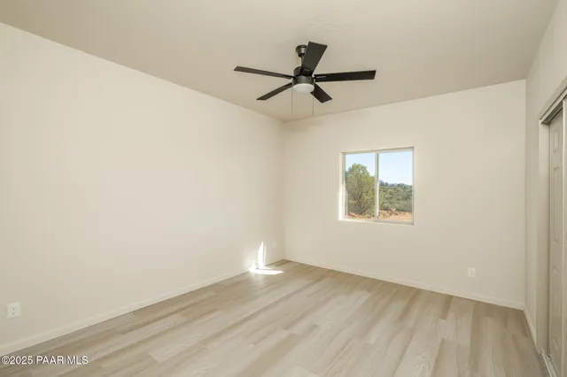 a view of a livingroom with a ceiling fan and kitchen space