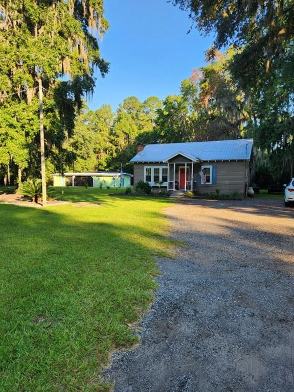 a view of swimming pool with lawn chairs and large trees