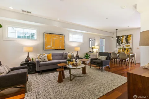 a living room with furniture couches and a dining table with wooden floor