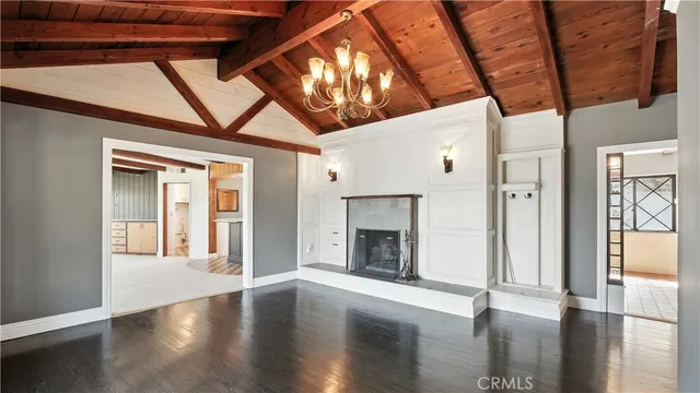 a view of an empty room with wooden floor fireplace and a window