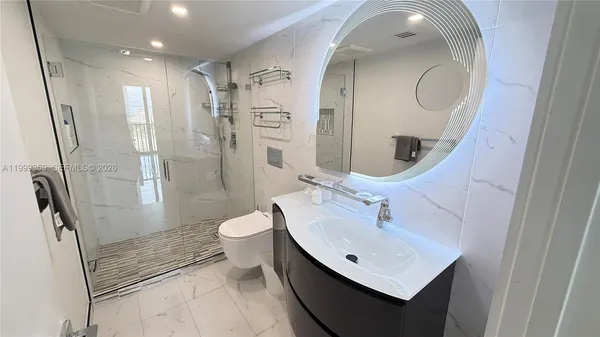 a bathroom with a sink a toilet and shower a mirror