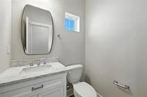 a bathroom with a granite countertop toilet a sink and mirror