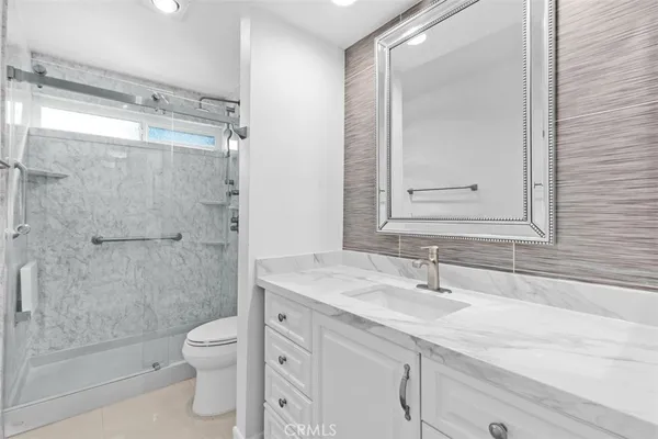 a bathroom with a granite countertop sink toilet and shower