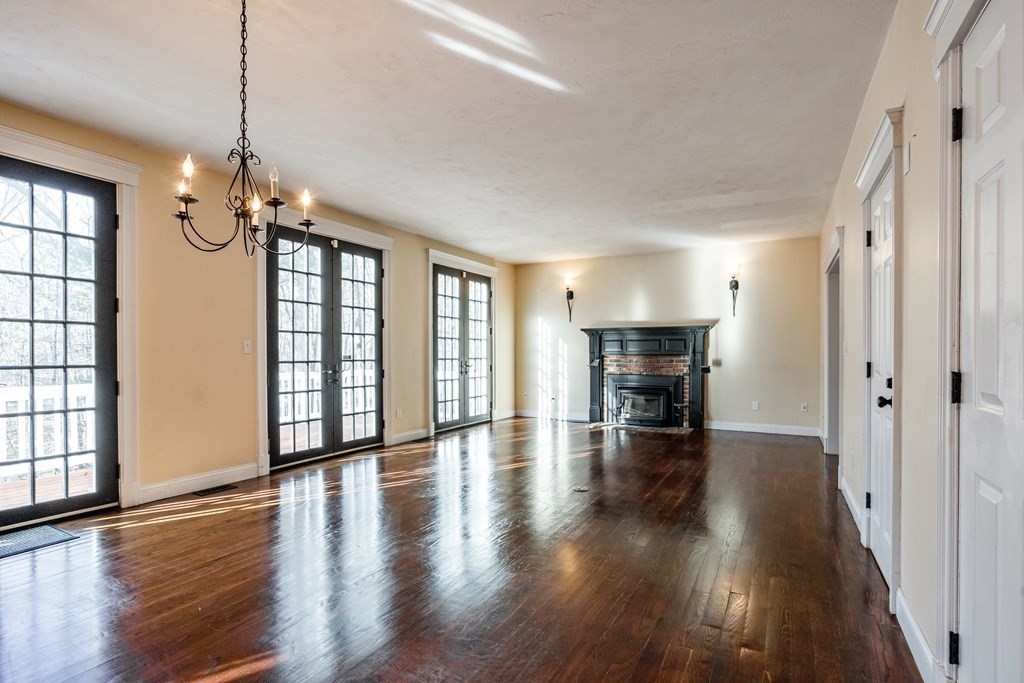 50 Corn Road Bolton, MA 01740 - Photo 8 of 40 a view of a livingroom with fireplace wooden floor and windows