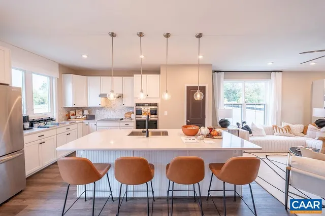 a large kitchen with granite countertop lots of white furniture appliances and a large window