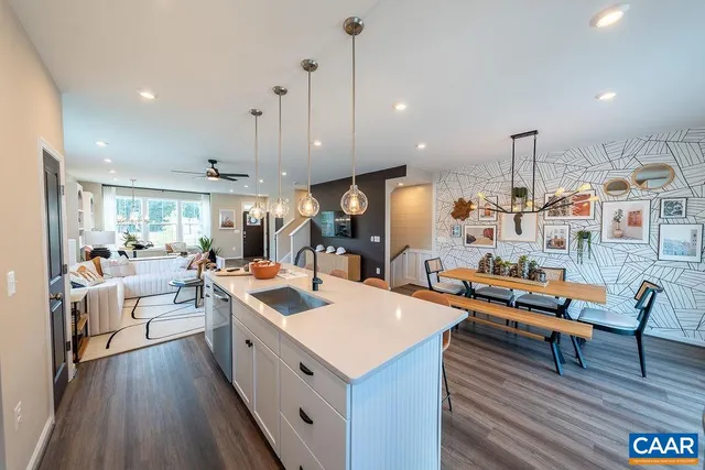 a view of a kitchen with kitchen island stainless steel appliances a dining table chairs sink and wooden floor