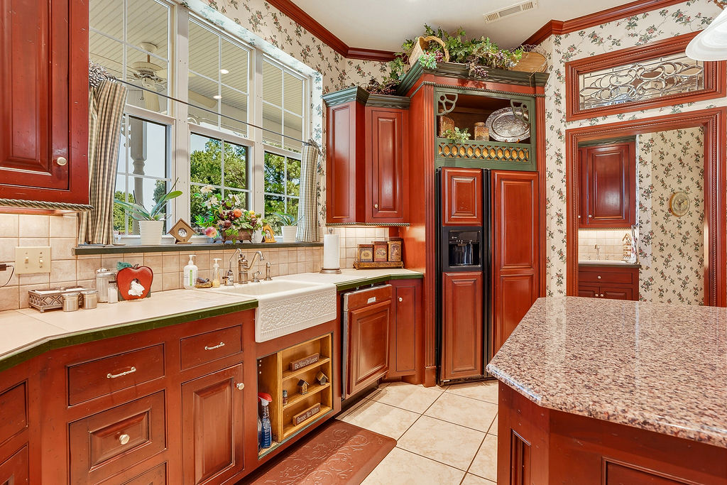 1009 Southeast County Road Ada, OK 74820 - Photo 18 of 92 Hardwood cabinetry with integrated refrigerator, ceramic tile flooring, farmhouse sink, granite island countertop, and tiled backsplash