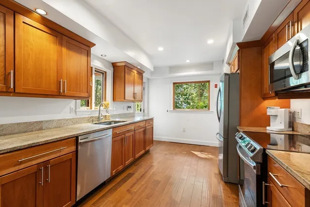 a kitchen with stainless steel appliances granite countertop wooden cabinets a sink and a window