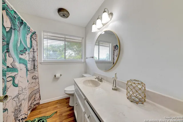 a bathroom with a granite countertop sink mirror and toilet
