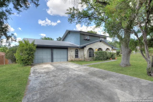 a view of a house with a yard and large tree