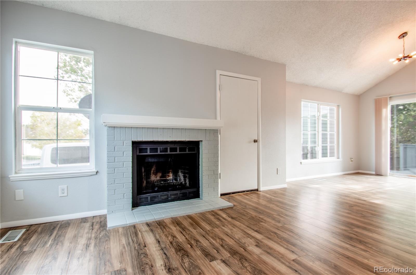 13309 Birch Circle Thornton, CO 80241 - Photo 6 of 25 an empty room with wooden floor fireplace and windows