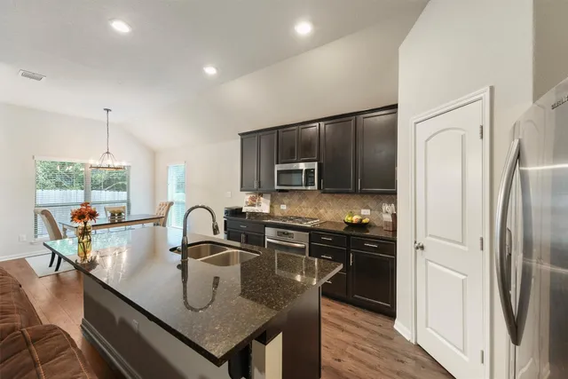 a kitchen with stainless steel appliances granite countertop a sink a stove and refrigerator