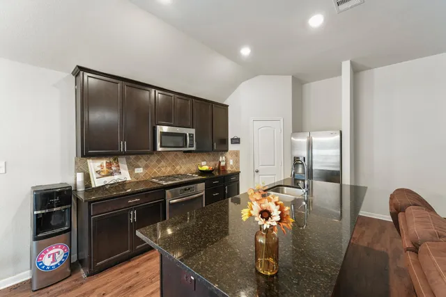 a kitchen with stainless steel appliances granite countertop a sink refrigerator and microwave
