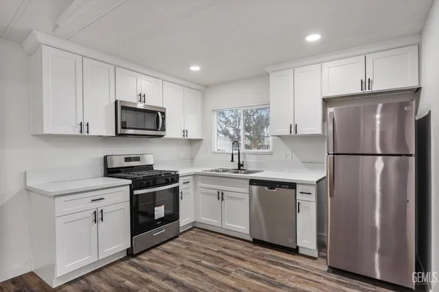 a kitchen with stainless steel appliances granite countertop a refrigerator stove a sink and white cabinets