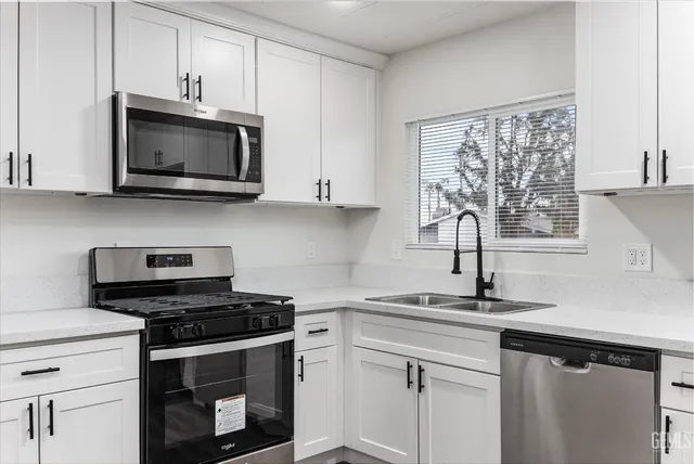 a kitchen with stainless steel appliances granite countertop white cabinets and a stove top oven