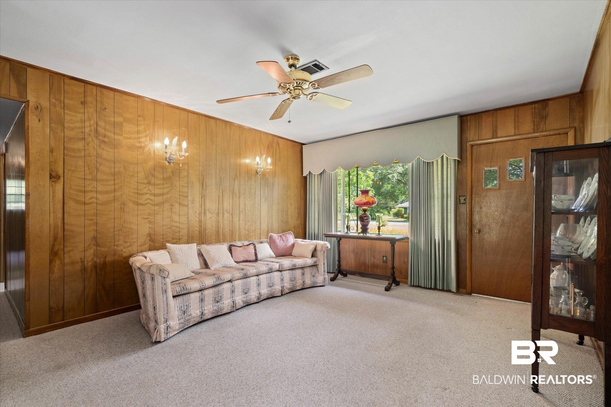423 First Avenue Saraland, AL 36571 - Photo 4 of 20 Carpeted living area with wood walls, a ceiling fan, and a chandelier