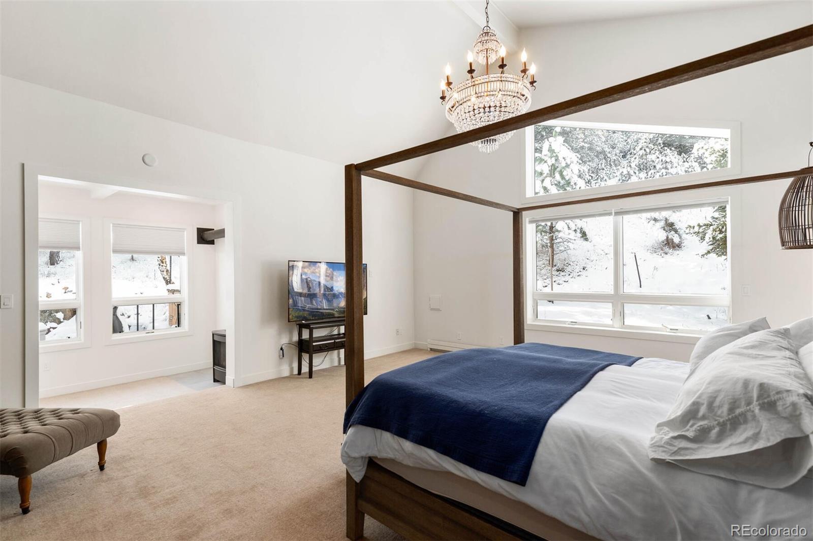 1791 Kerr Gulch Road Evergreen, CO 80439 - Photo 15 of 40 a bedroom with a large bed and a chandelier