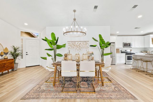 a living room with furniture a potted plant and open kitchen view
