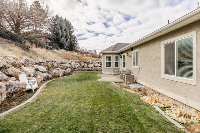 240 Bugle Way Providence, UT 84332 - Photo 8 of 15 Expansive backyard featuring a manicured lawn, a large stone retaining wall, and a concrete patio