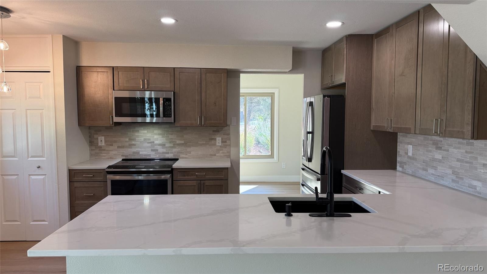 15789 Sandtrap Way Morrison, CO 80465 - Photo 35 of 42 a kitchen with stainless steel appliances kitchen island granite countertop a refrigerator and a stove top oven