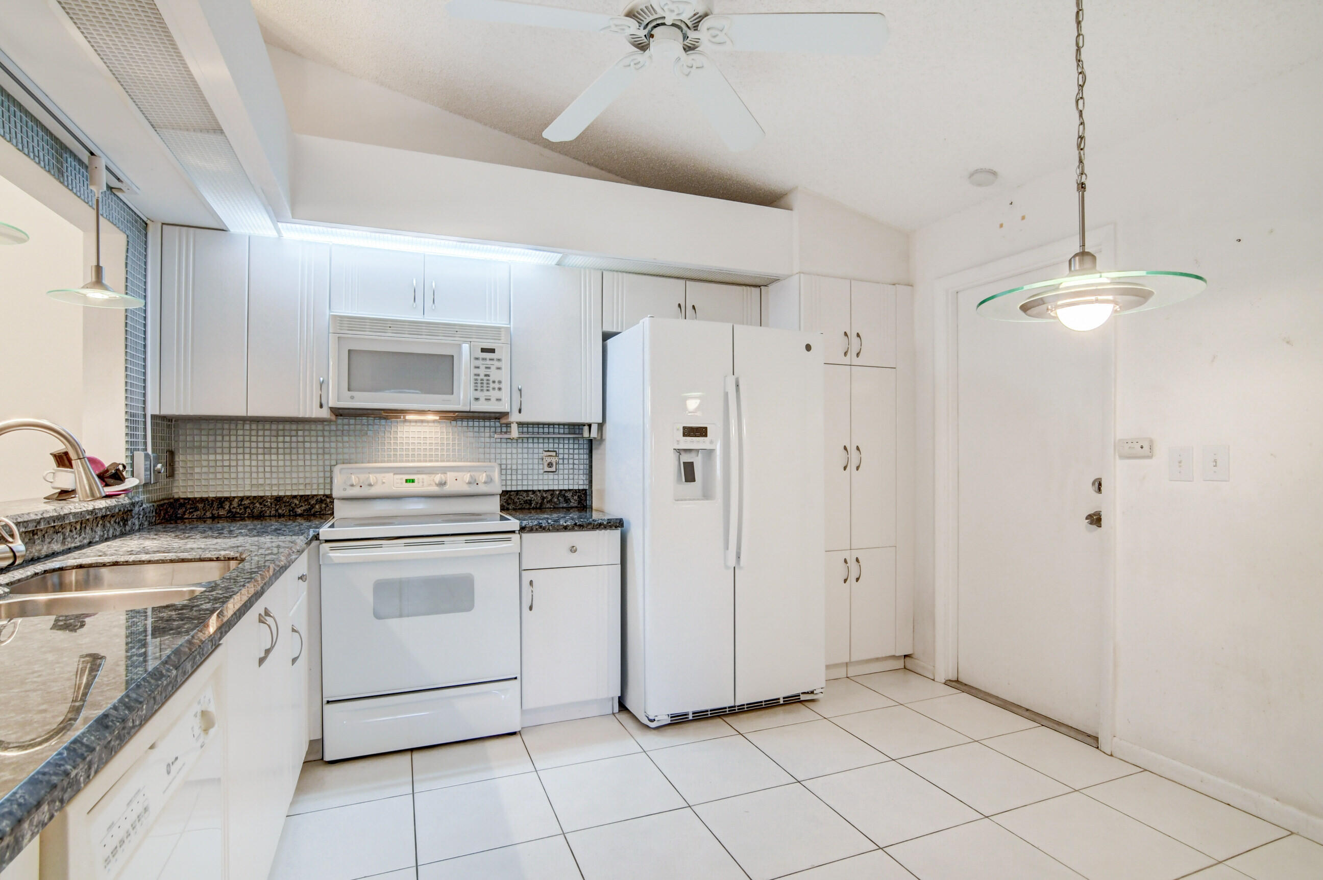 7566 Red Ruby Drive Delray Beach, FL 33446 - Photo 18 of 44 a kitchen with white cabinets and white appliances