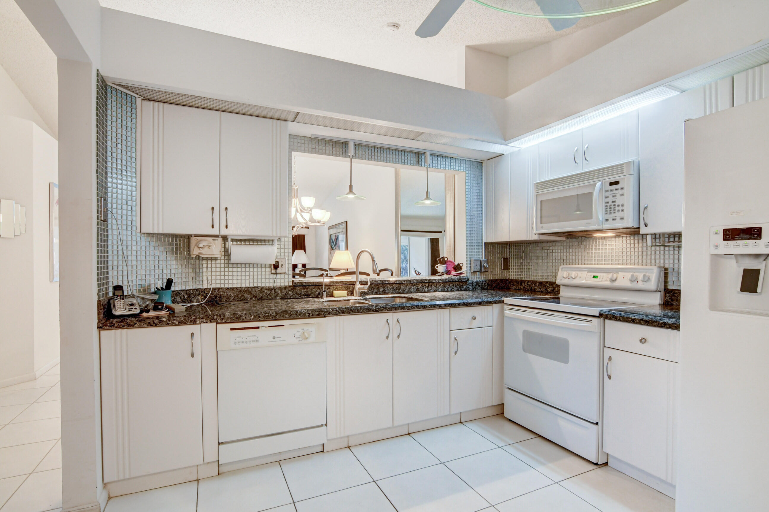 7566 Red Ruby Drive Delray Beach, FL 33446 - Photo 19 of 44 a kitchen with granite countertop white cabinets sink and stainless steel appliances