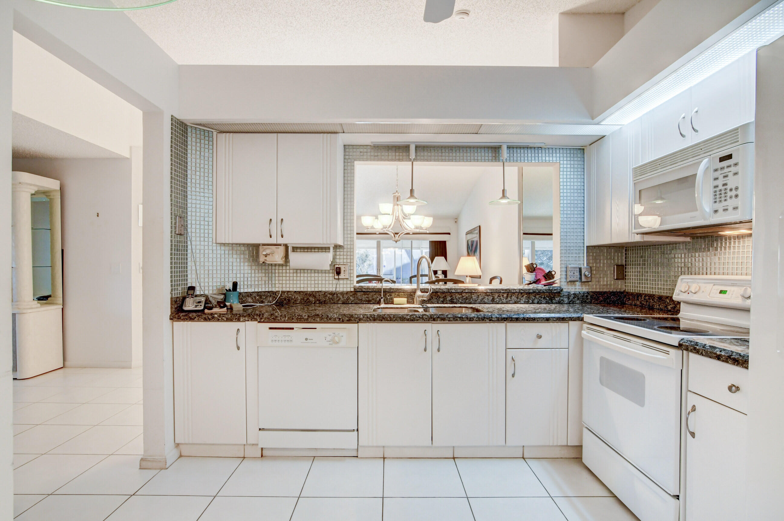 7566 Red Ruby Drive Delray Beach, FL 33446 - Photo 20 of 44 a kitchen with granite countertop white cabinets and white appliances