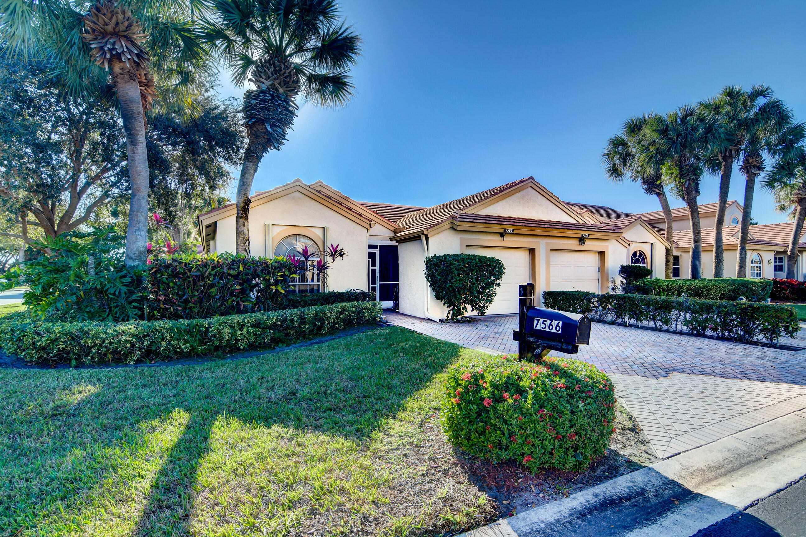 7566 Red Ruby Drive Delray Beach, FL 33446 - Photo 5 of 44 a front view of a house with a garden and patio