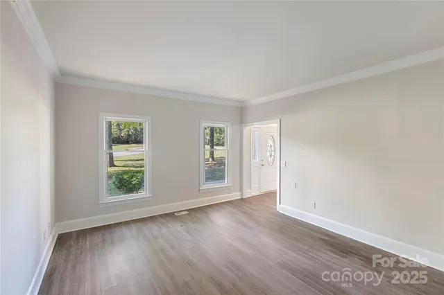 an empty room with wooden floor and window
