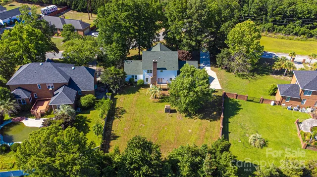 an aerial view of residential houses with outdoor space and trees all around