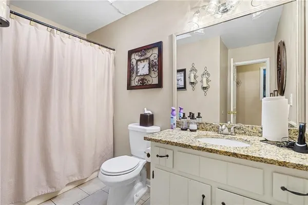 a bathroom with a granite countertop sink toilet and mirror