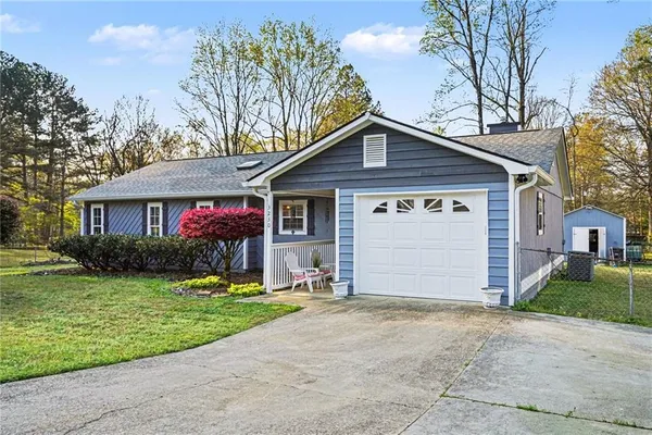 a front view of a house with a garden and trees