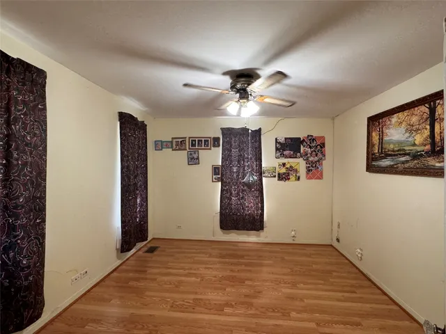 a view of an empty room with window and a ceiling fan