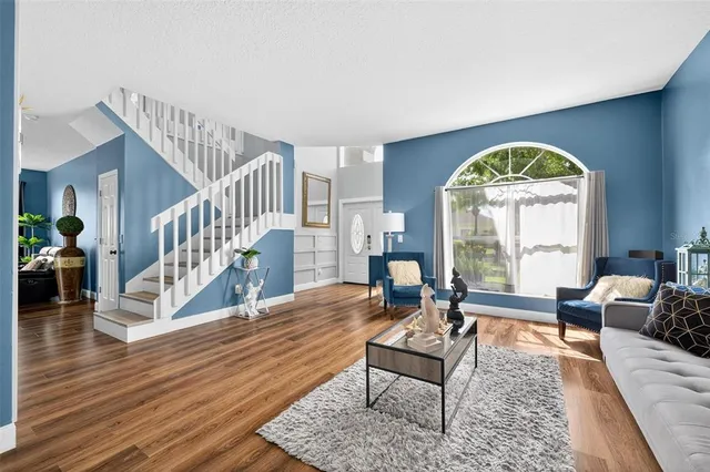 a living room with wooden floor and a chandelier