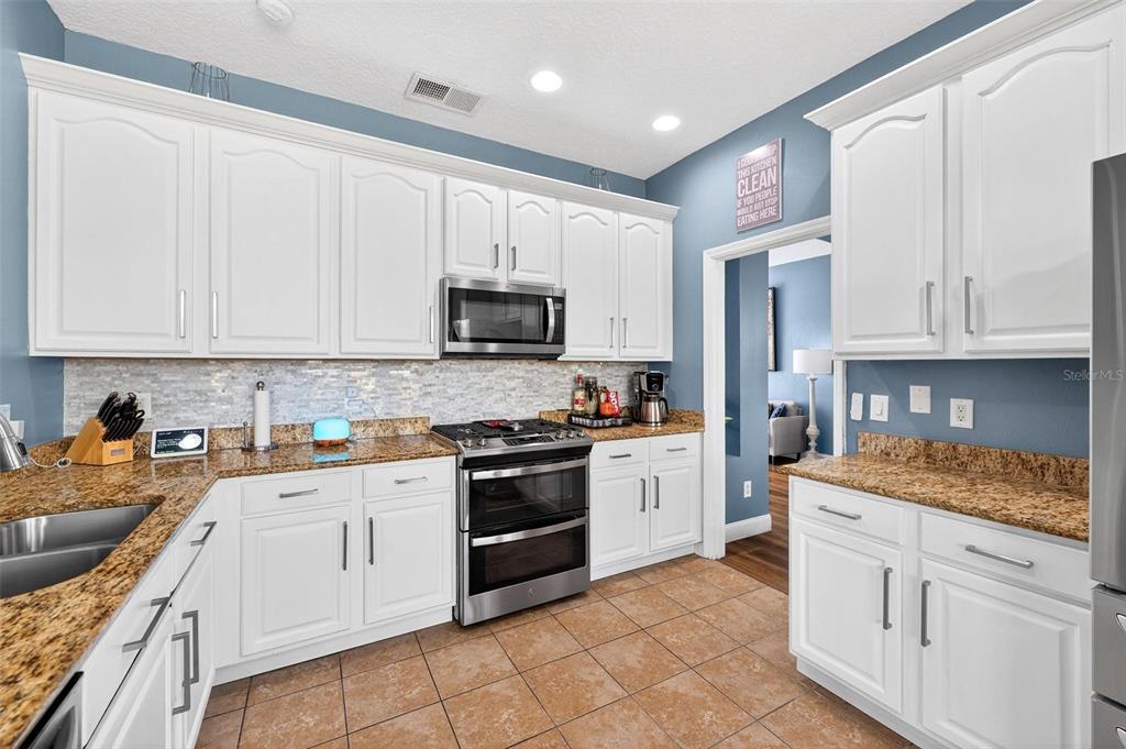 413 Rockafellow Way Orlando, FL 32828 - Photo 40 of 88 a kitchen with stainless steel appliances granite countertop a stove top oven a sink dishwasher and a refrigerator with wooden cabinets