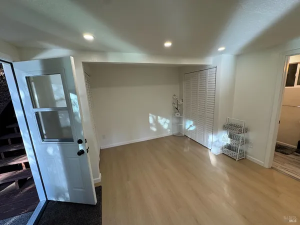 a view of an empty room with wooden floor and a staircase