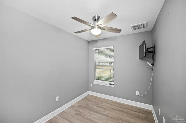 a view of empty room with wooden floor and fan