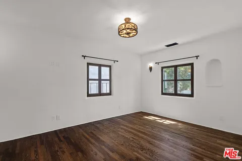 a view of an empty room with window and wooden floor