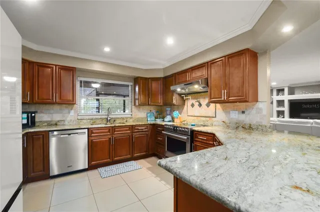 a kitchen with stainless steel appliances granite countertop sink stove top oven refrigerator and cabinets