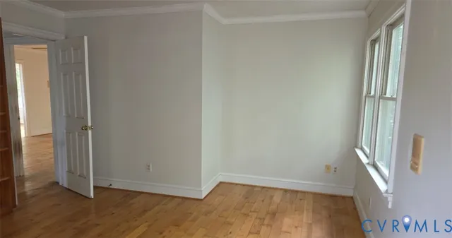 a view of an empty room with a window and wooden floor