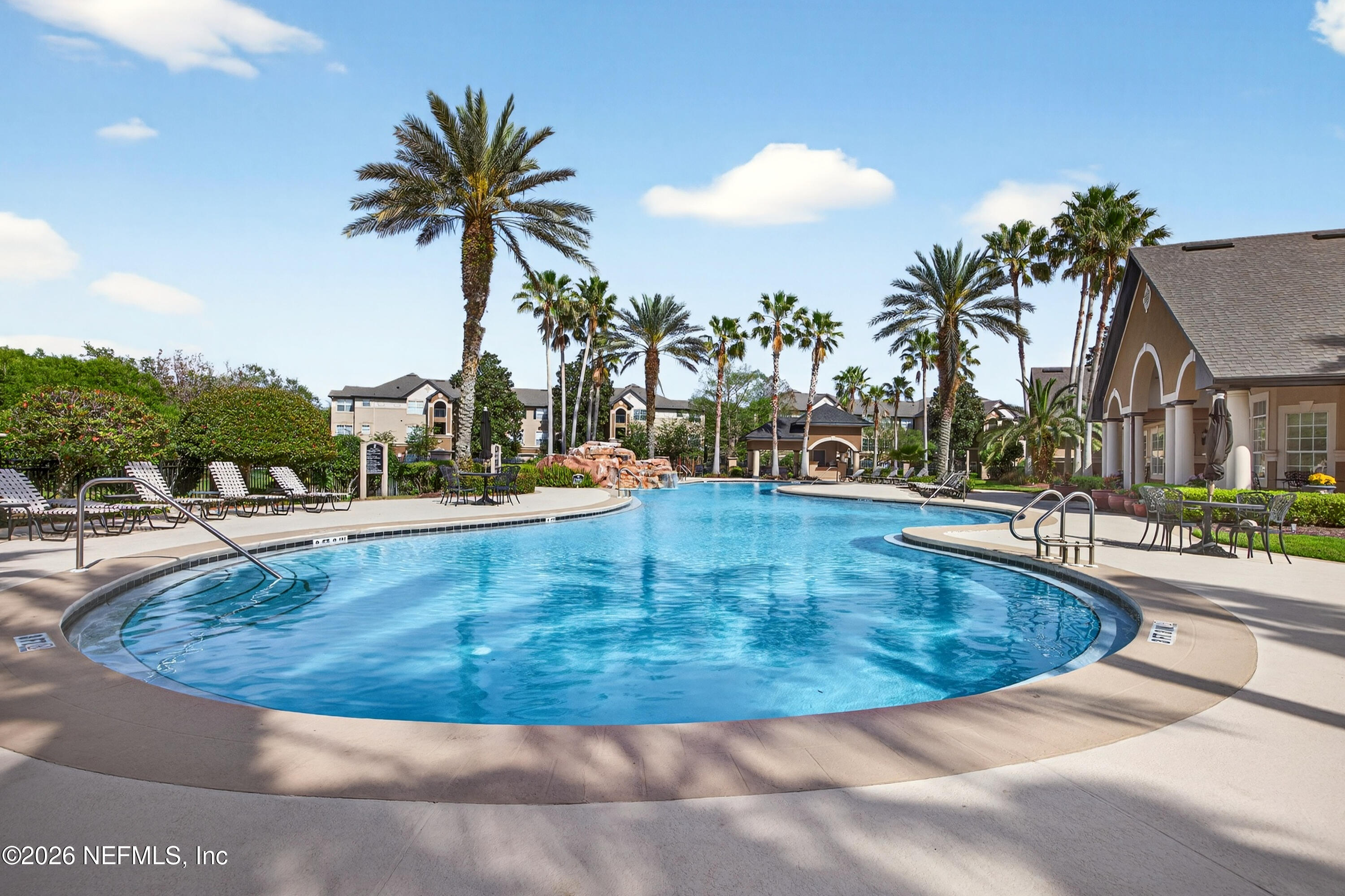 10961 Burnt Mill Road, Unit 1524 Jacksonville, FL 32256 - Photo 25 of 38 a view of a swimming pool with a lawn chairs under palm trees