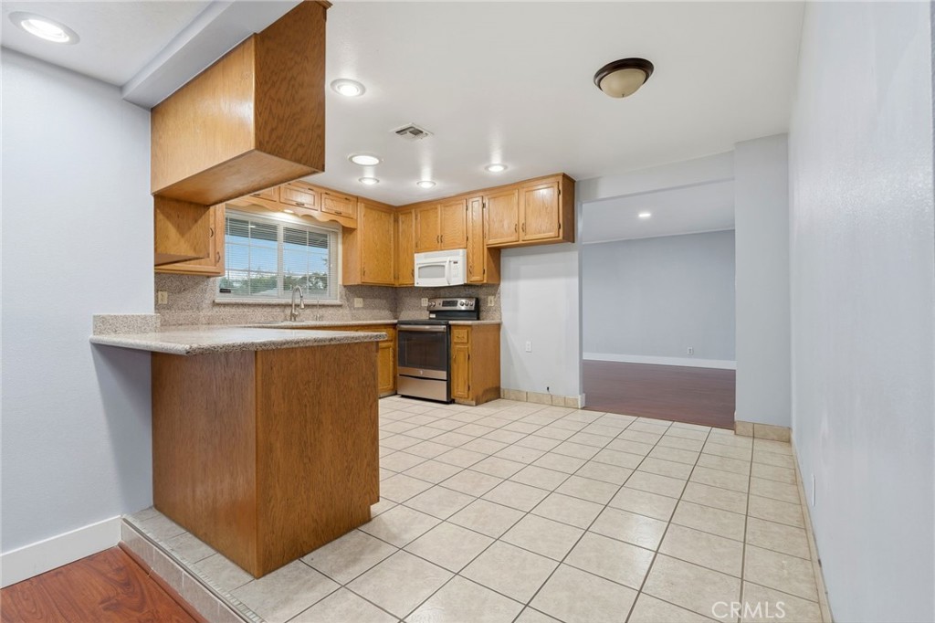 2826 East Hampton Way Fresno, CA 93726 - Photo 14 of 29 a kitchen with stainless steel appliances a sink a stove a refrigerator cabinets and a window