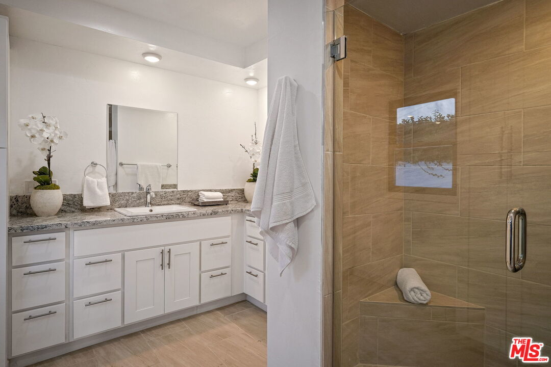 543 Westmount Drive West Hollywood, CA 90048 - Photo 20 of 44 a bathroom with a granite countertop sink a mirror and a shower