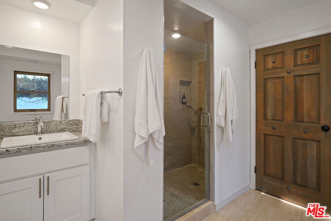 543 Westmount Drive West Hollywood, CA 90048 - Photo 22 of 44 a bathroom with a granite countertop sink mirror and shower