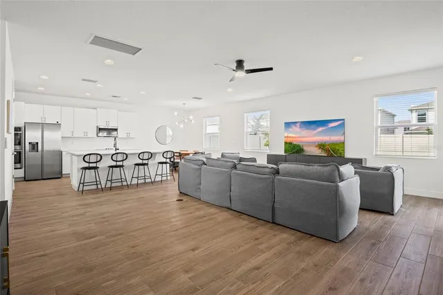 a kitchen with stainless steel appliances granite countertop a dining table chairs refrigerator sink and cabinets