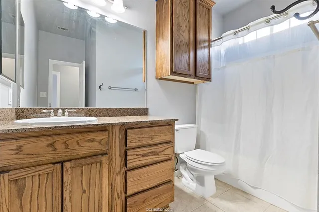 a bathroom with a granite countertop toilet a sink and a mirror