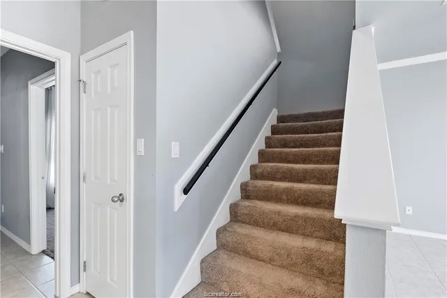 a view of staircase with white walls and white door