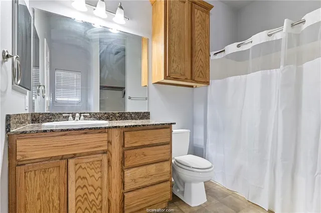 a bathroom with a granite countertop sink toilet a mirror and shower