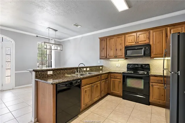 a kitchen with stainless steel appliances granite countertop a stove a sink and a microwave
